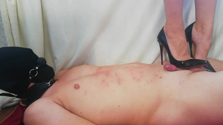 Trampling a slave. Mistress in black louboutins with high heels. Scratches on the stomach.
