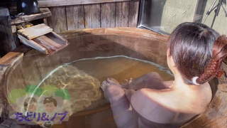 An amateur Japanese woman taking a leisurely bath at a hot spring inn with an open-air bath.