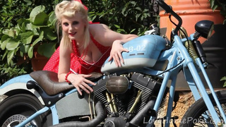 Cute blonde enjoys posing next to a bike