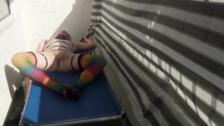 Caged sissy plays with her dildo on public balcony